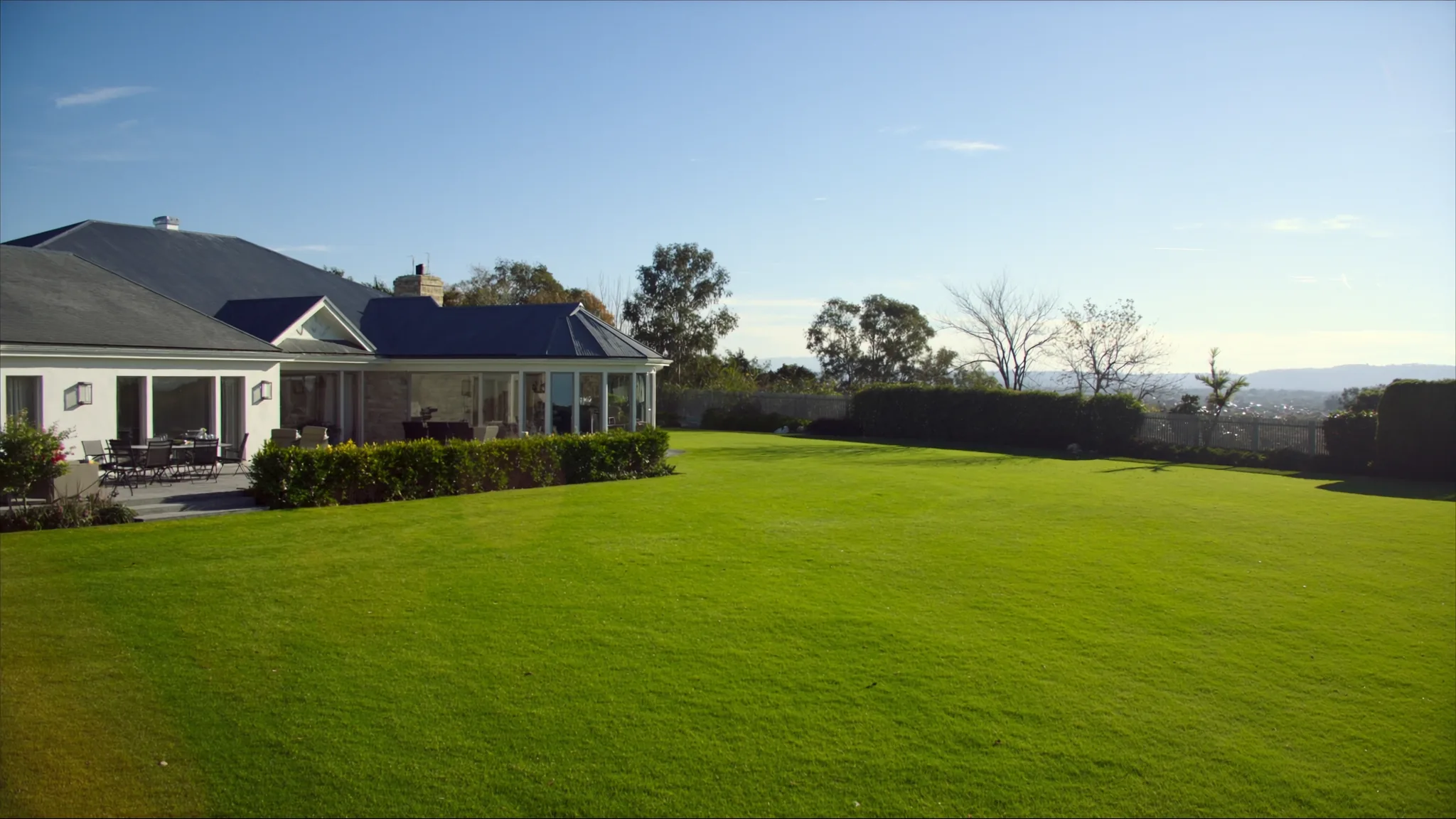 An established family home with a paved patio and a wide lawn